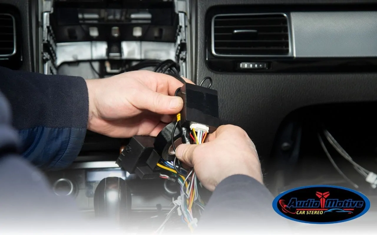 Professional installing amplifier and wiring in car trunk