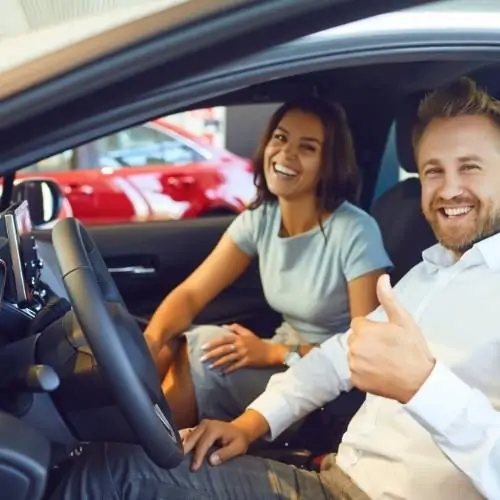 Smiling couple sitting in their car, excited about their newly installed stereo system